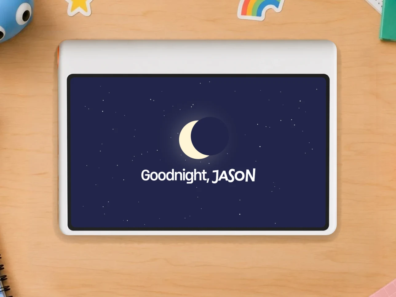 Kale on a wooden desk ringed with toys and art supplies, its screen showing a sleepy axolotl and “Explore time is up. What next?” with buttons for Apps, Sleep mode and a reset